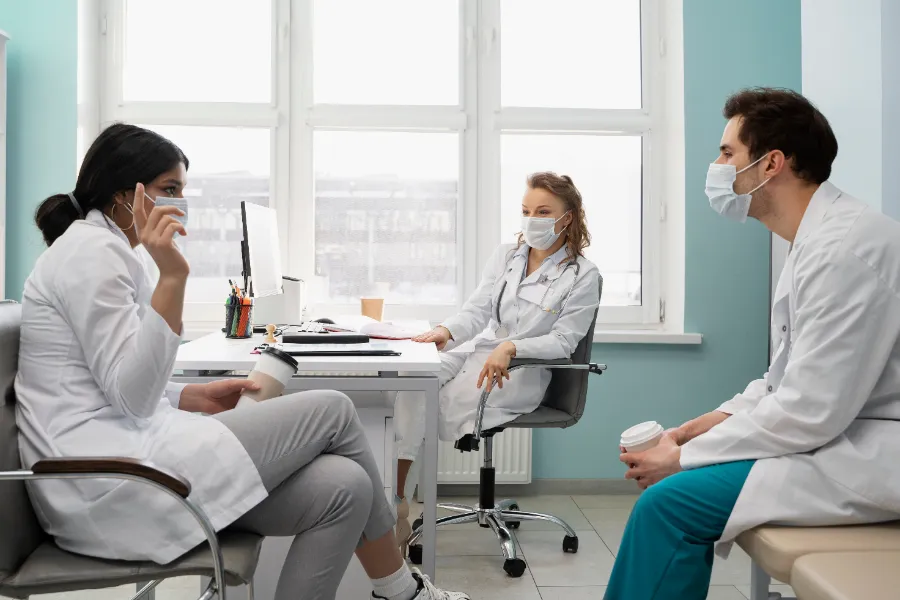 Three physicians talking together in a group practice office