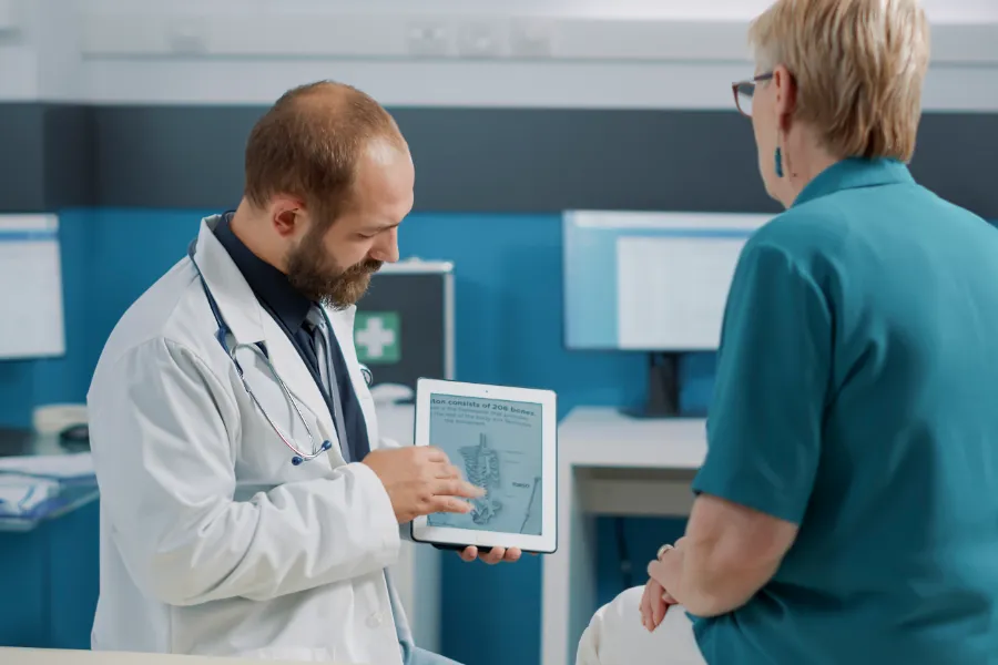 Specialist physician showing a skeletal scan on a tablet to a patient